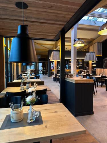 a restaurant with wooden tables and chairs and black lights at Vareler Brauhaus-Hotel Varel Dangast in Varel
