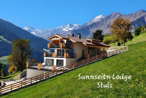 a house on a hill with mountains in the background at Sunnseitn Lodge Apt Mountainsuite in Stulles