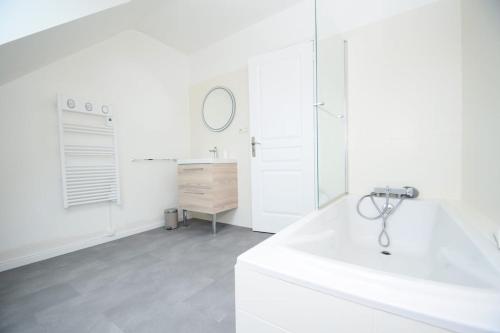 une salle de bain blanche avec un lavabo et un miroir dans l'établissement Maison rénovée 6 personnes proche des plages, à Ploubalay