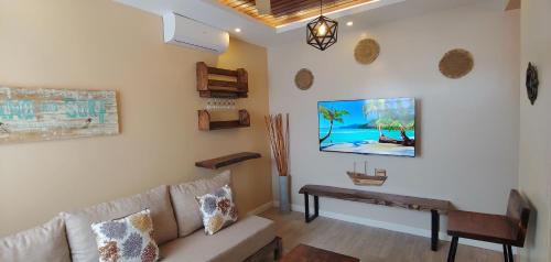 a living room with a couch and a tv on the wall at Serene Furnished Apartments in Vipingo