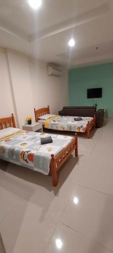 three beds sitting in a room with a tv at Glossy Marina Homestays in Lumut