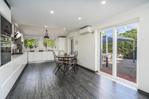 a kitchen with white cabinets and a table and chairs at Villa Felicity in Porches