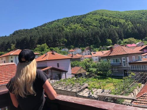 a woman standing on a balcony looking at a village at Guesthouse Gaby in Sapareva Banya