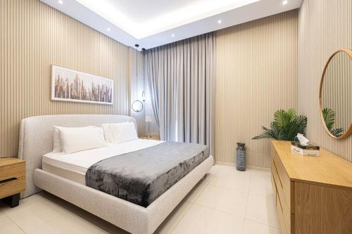 a bedroom with a bed and a mirror at Luxury Huge 1BR apartment With Private Garden in Uptown Al Zahia in Sharjah