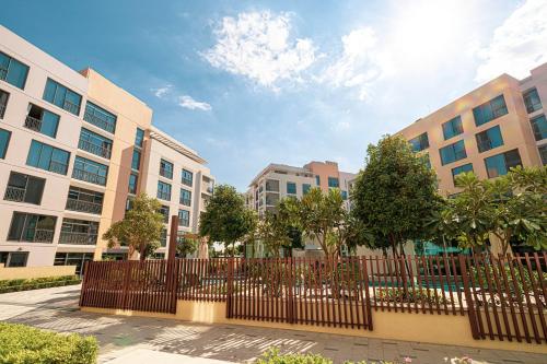 a fence in front of some buildings with trees at Luxury Huge 1BR apartment With Private Garden in Uptown Al Zahia in Sharjah
