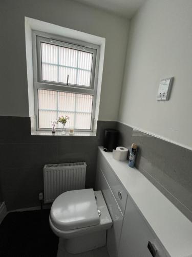 a bathroom with a white toilet and a window at Cosy family home in Buckingham in Buckinghamshire