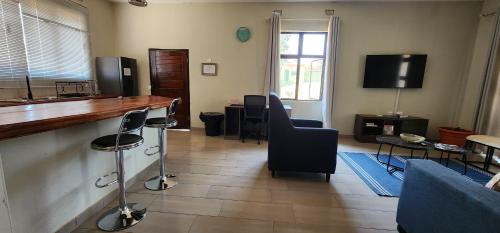 a living room with a bar with chairs and a tv at Fully Furnished Apartments in Manyama, Lumwana Mine in Chanamo