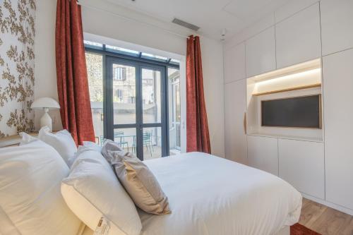 a bedroom with a white bed and a television at Villa Victor Hugo by Odomo in Avignon