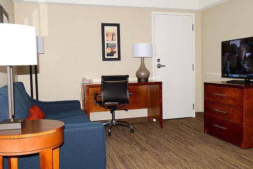 a hotel room with a blue couch and a desk at Comfort Inn University Durham - Chapel Hill in Durham