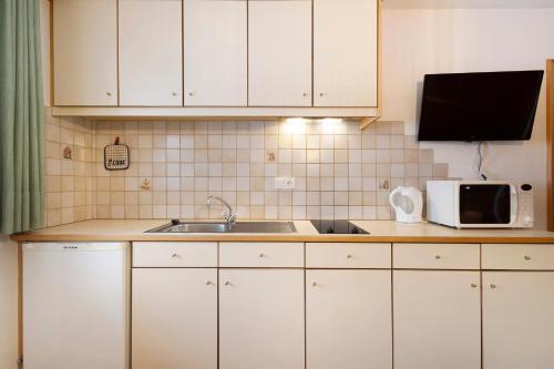 a kitchen with white cabinets and a sink and a microwave at Untersinnerhof Gsies in Valle Di Casies