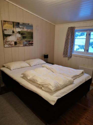 a large bed in a bedroom with a window at Kaikanten Rorbuer in Sennesvik