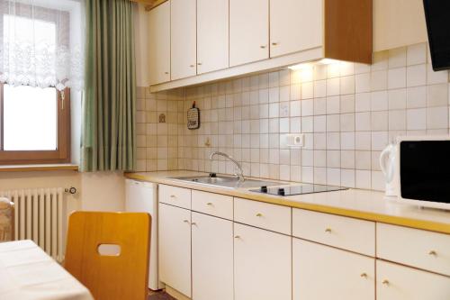 a kitchen with white cabinets and a sink at Untersinnerhof Gsies in Valle Di Casies