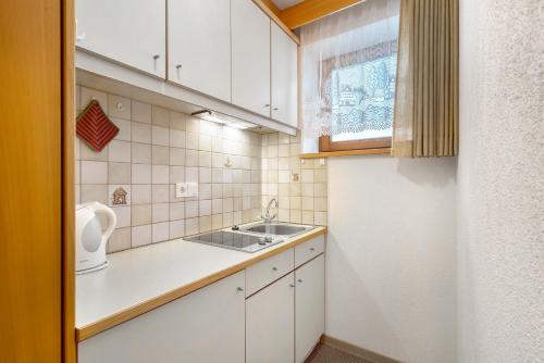 a small kitchen with white cabinets and a sink at Untersinnerhof Gsies in Valle Di Casies