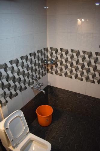 a bathroom with a toilet and an orange bucket at Hill side Home in Anachal