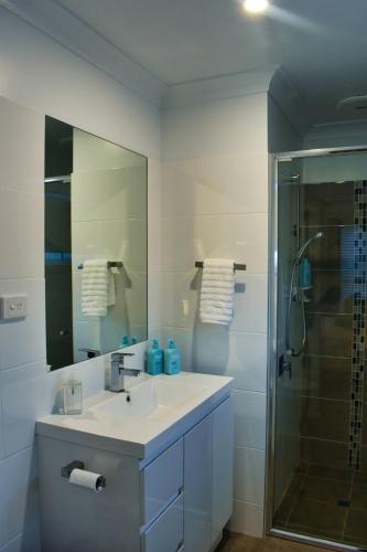 a white bathroom with a sink and a shower at Paperbark Cottage in Callala Bay
