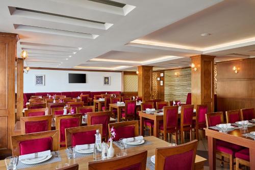 a restaurant with wooden tables and red chairs at Deventure Shimla Hills in Kandāghāt