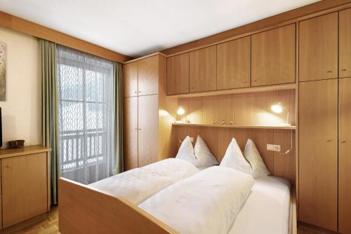 a bedroom with a bed with white sheets and a window at Untersinnerhof Gsies in Valle Di Casies