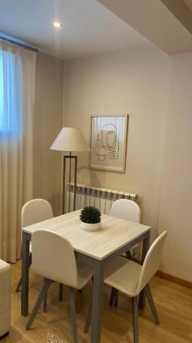 a dining room table with white chairs and a lamp at Apartamentos Turisticos de Soria Collado 3 in Soria