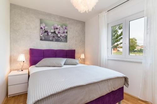 a bedroom with a purple bed and a window at Villa Leoni by IstriaLux in Orihi