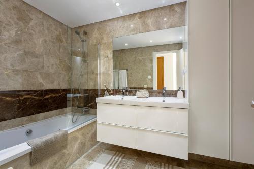 a bathroom with a sink and a tub and a mirror at Sun-Soaked Home - Panoramic Sea View, Pool, Parking in Manilva
