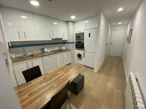 a kitchen with white cabinets and a wooden table at Apartamentos Turisticos de Soria Estudios 6 in Soria