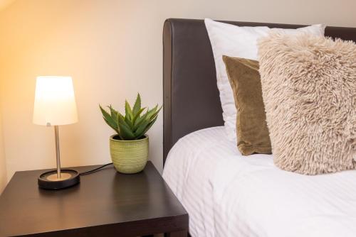a bed with a table with a lamp and a plant on it at Hotel & Apartments Bibois Leuven in Oud-Heverlee