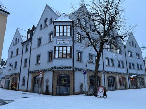 a large white building with a tree in the snow at Altstadthotel Bräuwirt in Weiden