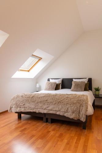 a bed in a white room with a skylight at Hotel & Apartments Bibois Leuven in Oud-Heverlee