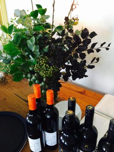 a bunch of wine bottles on a table with a vase at Cascades Motor Inn in Dubbo