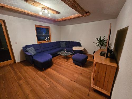 a living room with a blue couch and a table at Haus Gaichtspitzblick in Weissenbach am Lech