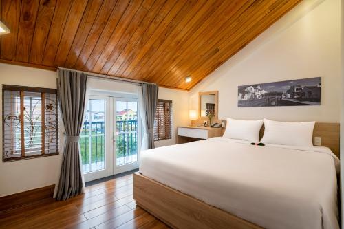 a bedroom with a large white bed and a window at Truc Loc Villa in Hoi An