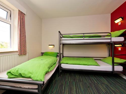 two bunk beds in a room with green pillows at YHA Sheringham in Sheringham