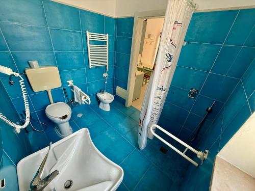 a blue bathroom with a sink and a toilet at Baia Sangiorgio Hotel & Beach Club in Bari