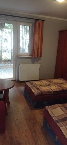 a room with two beds and a table and a window at Zajazd U Doktora in Lubrza