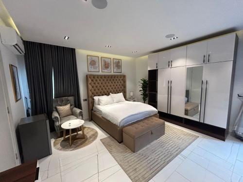 a bedroom with a bed and a chair in it at VACATION HOMES - 5 bedroom private compound home in lekki phase 1 - rooftop, pool, spa, cinema, 24h light & security in Lekki Phase 1