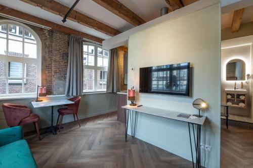 a living room with a desk and chairs and windows at Studio Urbain in Alkmaar