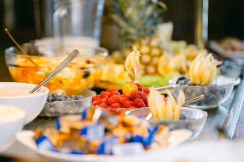 a buffet of food with bowls of fruit on a table at Ambiance Hotel - Braunau - Simbach in Braunau am Inn