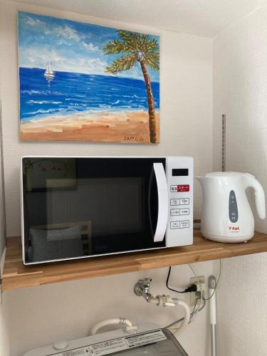 a microwave on a shelf with a picture of a beach at Tokyo Disney Resort 3 minutes by train, along Symbol Road, and plenty of commercial facilities!Free wifi, double bed in Tokyo