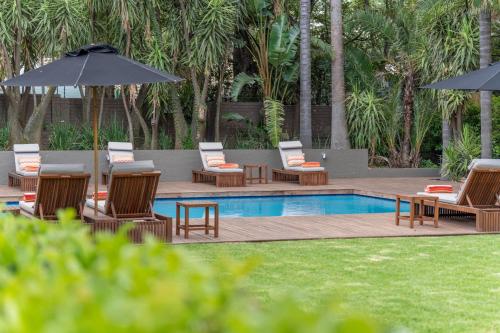 a pool with lounge chairs and umbrellas next to at AtholPlace Hotel & Villa in Johannesburg