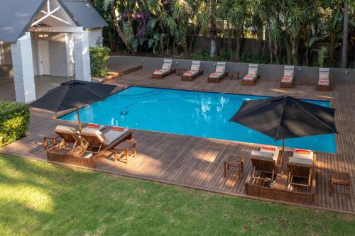 a swimming pool with chairs and umbrellas on a deck at AtholPlace Hotel & Villa in Johannesburg