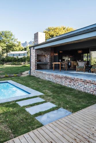 a backyard with a pool and a brick house at Bains View Olive and Guest Farm in Wellington