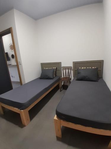 two beds sitting in a room with a chair at Casa nova a 2 min do mar in Arroio do Sal