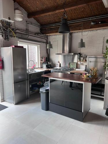 a kitchen with stainless steel appliances and a wooden table at Finca Noordwijk met privé tuin, dichtbij strand in Noordwijk