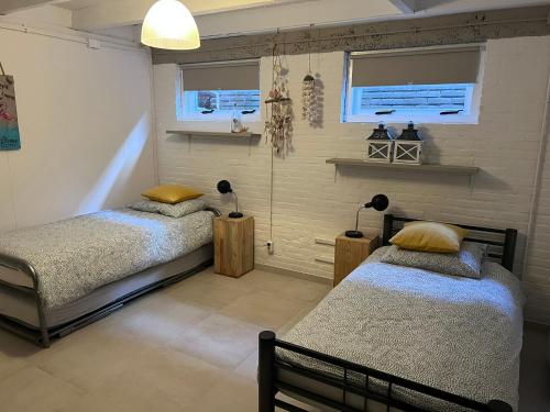 a bedroom with two beds and two windows at Finca Noordwijk met privé tuin, dichtbij strand in Noordwijk