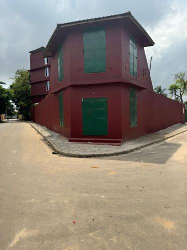a red building with green doors on a street at Motel Africa pas Chers in Conakry
