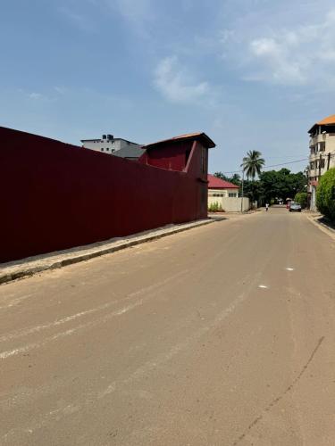 an empty street next to a red wall at Motel Africa pas Chers in Conakry