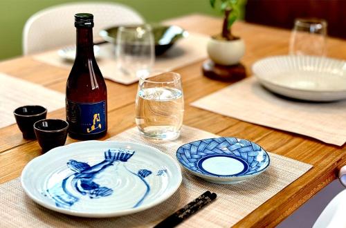 a table with a bottle of wine and plates on it at Hosted Stay Minpaku Hallelujah in Matsumoto