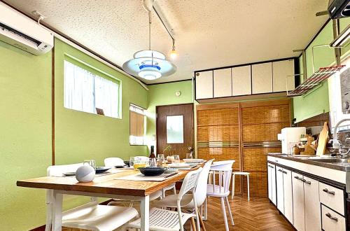a kitchen with a wooden table and white chairs at Hosted Stay Minpaku Hallelujah in Matsumoto