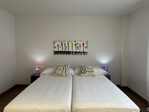 a white bed in a bedroom with a painting on the wall at Yvacas 1A in Tudela