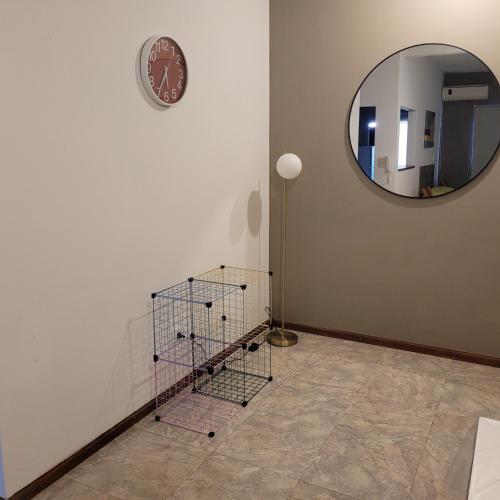 a mirror and a basket on a wall with a clock at Dpto Centeno Centrico 3 B in Santa Rosa